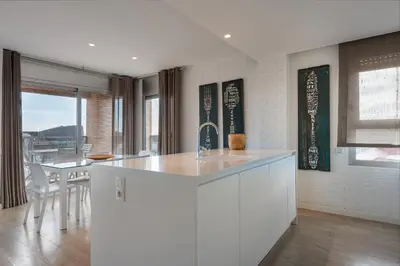 a white kitchen with a sink and a table at Enjoybcn Marina Apartment in Barcelona