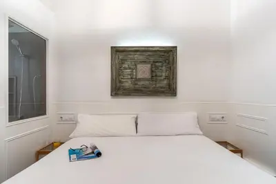a white bed in a room with a window at Enjoybcn Tallers Apartment in Barcelona