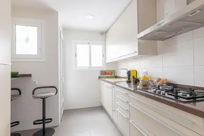 a white kitchen with white cabinets and a stove at Housalia Guell Gaudi in Barcelona