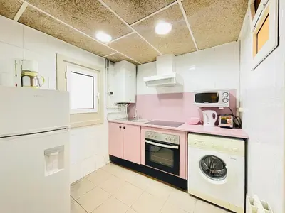 a pink and white kitchen with a washer and dryer at Smartr Barcelona Ramblas in Barcelona