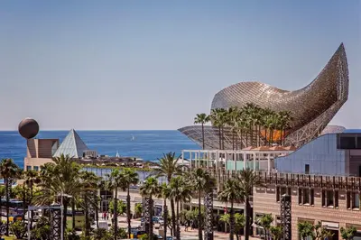 a view of a building with palm trees and the ocean at Sweett - Villa Olimpica Mediterranean in Barcelona