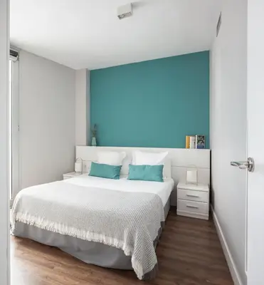 a white bedroom with a large bed with blue walls at Feelathome Poblenou Beach Apartments in Barcelona