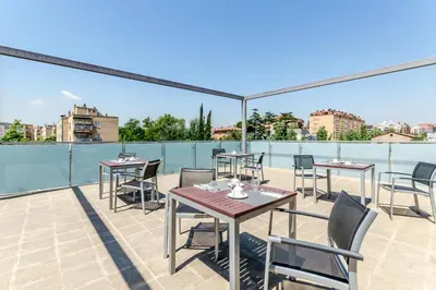 a patio with tables and chairs on a roof at Eurostars Executive in Barbera del Valles