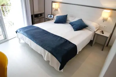 a bedroom with a large bed with blue pillows at Parrots Sitges Hotel in Sitges