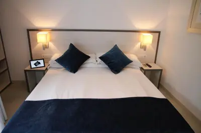 a bedroom with a large bed with blue pillows at Parrots Sitges Hotel in Sitges