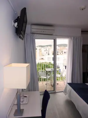 a bedroom with a bed and a desk with a television at Parrots Sitges Hotel in Sitges