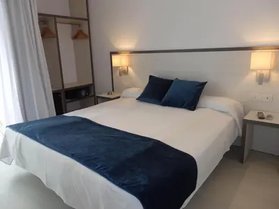 a bedroom with a large white bed with blue pillows at Parrots Sitges Hotel in Sitges