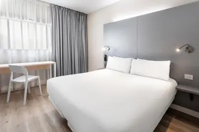 a hotel room with a large white bed and a desk at B&B HOTEL Barcelona Mollet in Mollet del Vallès