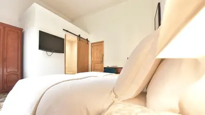 a bedroom with a white bed and a tv at Hostal Girona in Barcelona