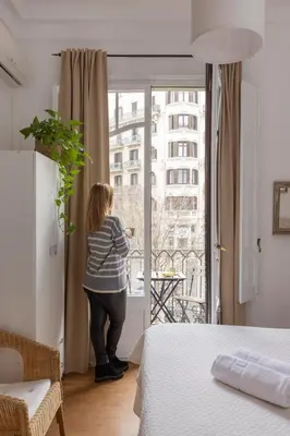 a woman standing in a bedroom looking out the window at Ally's Bed&Breakfast, in Barcelona