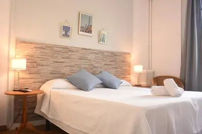a bedroom with a white bed and a brick wall at Ally's Bed&Breakfast, in Barcelona