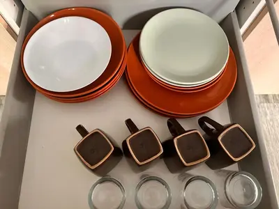 a set of plates and bowls in a drawer at Apartaments IRI in Pineda de Mar