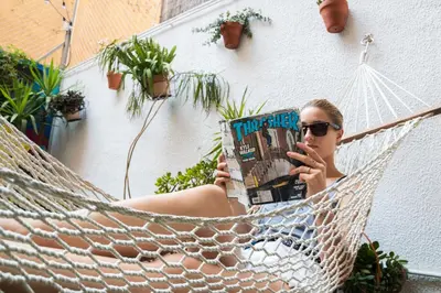 a woman laying in a hammock reading a magazine at Sant Jordi Hostels Sagrada Familia in Barcelona
