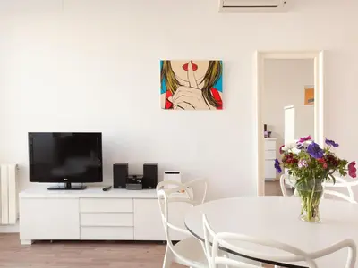 a white dining room with a table and a vase of flowers at Stay U-nique Apartments Sant Pau in Barcelona