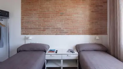 two beds in a room with a brick wall at Hotel Sagrada Familia Apartments in Barcelona