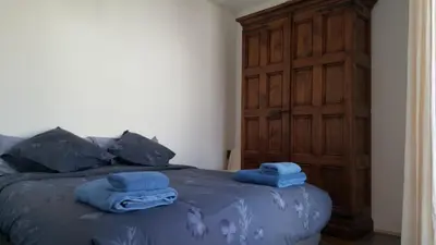 a bedroom with a bed with blue sheets and a wooden door at The Sky Attic Apartment in Sitges