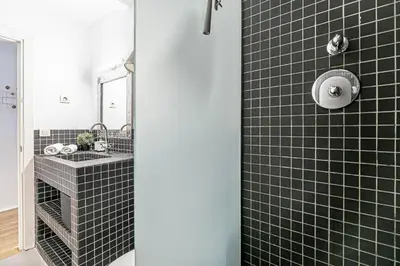 a bathroom with a black tiled shower with a sink at Super central 3BR apartment, spacious and bright in Barcelona