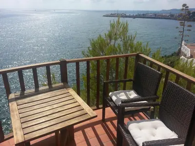 two chairs and a bench on a balcony overlooking the water at Sitges Balcony Pool & Seaside Apartment in Sitges