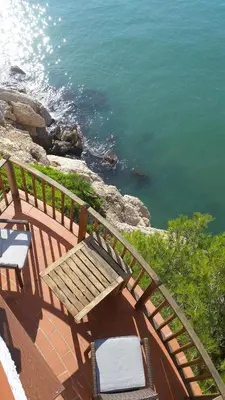 a wooden bench sitting on a balcony overlooking the water at Sitges Balcony Pool & Seaside Apartment in Sitges