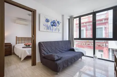 a living room with a blue couch and a bed at Matarolux 6 in Mataró