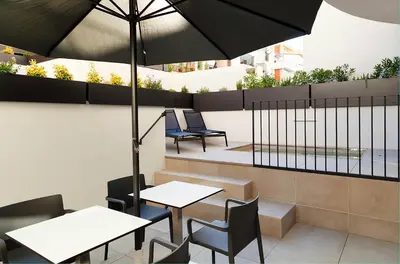 a patio with tables and chairs and an umbrella at Vila Arenys Hotel in Arenys de Mar