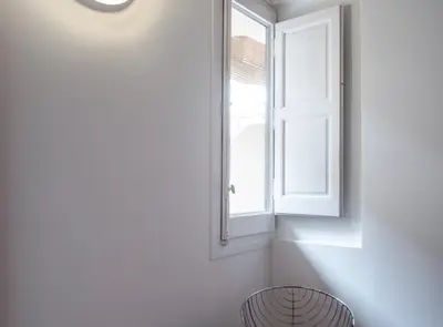 a white room with a window and a stool at Villaroel · Modern flat in San Antoni in Barcelona