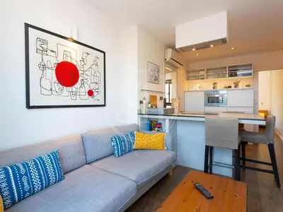 a living room with a couch and a kitchen at Attic Terrace Montjuïc in Barcelona