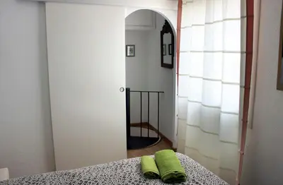 a bedroom with a bed with a green pillow on it at Mini Apartamento Port Aiguadolç in Sitges