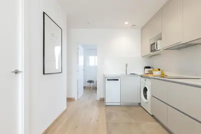 a kitchen with white cabinets and a washer and dryer at Housalia Familia Rossellon in Barcelona
