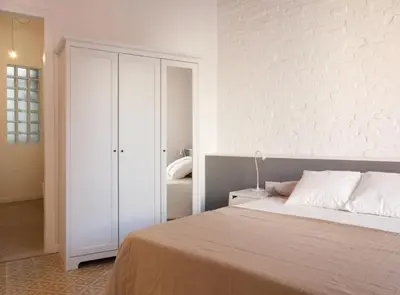 a bedroom with a bed and a white wall at Napoles · Modernist flat close to Sagrada Familia in Barcelona
