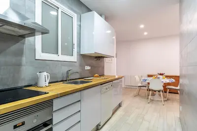 a kitchen with white cabinets and a sink and a table at 2215 - AB Calabria Apartment in Barcelona