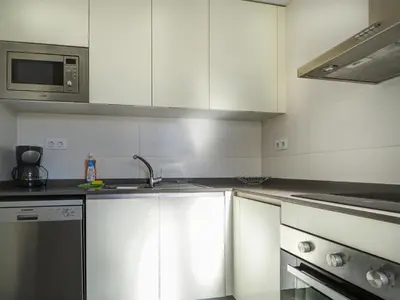 a kitchen with white cabinets and a sink and a microwave at Amazing Terrace in the Center by Hello Homes Sitges in Sitges
