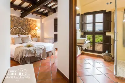 a bedroom with a bed and a bathroom with a sink at Masia Can Canyes & Spa in San Lorenzo de Hortóns