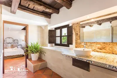 a bathroom with a tub and a sink and a bedroom at Masia Can Canyes & Spa in San Lorenzo de Hortóns