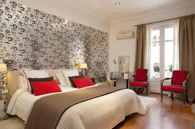a bedroom with a bed and two red chairs at HoHomes - Luxury Palacete in Barcelona