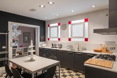a kitchen with black cabinets and a table with a table at HoHomes - Luxury Palacete in Barcelona