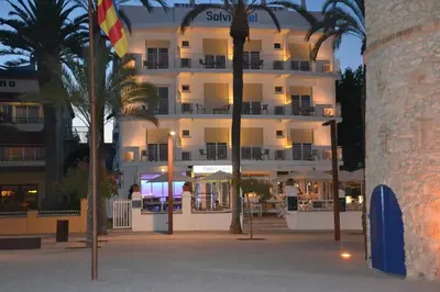 a large white building with palm trees in front of it at Solvi Hotel - Adults Only in Vilanova i la Geltrú