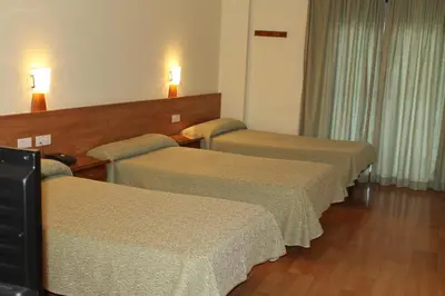 a hotel room with three beds and a television at Hotel Flora Parc in Castelldefels