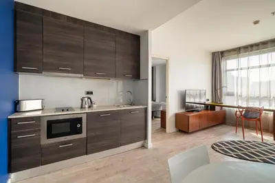 a kitchen with dark wood cabinets and a living room at Naitly Barcelona Poblenou in Barcelona