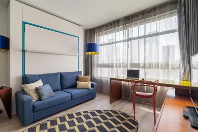 a living room with a blue couch and a desk at Naitly Barcelona Poblenou in Barcelona