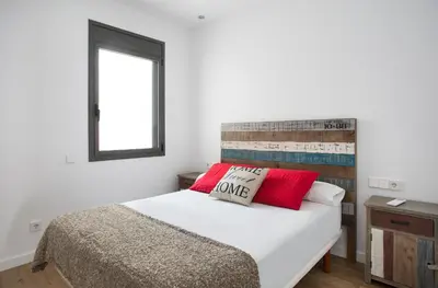 a bedroom with a bed with two red pillows at Sweet Home Sitges BY BLAUSITGES in Sitges