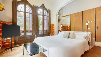 a bedroom with a large white bed and a flat screen tv at Le Palacete by Sweett in Barcelona
