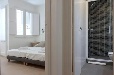 a bedroom with a bed and a bathroom with a sink at Flateli Roger 6 in Barcelona