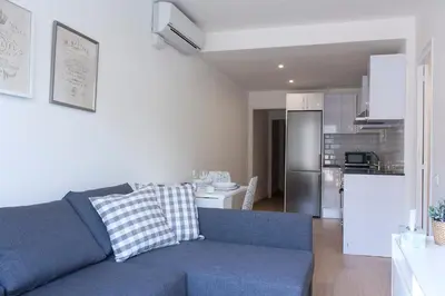 a living room with a blue couch and a kitchen at Flateli Roger 6 in Barcelona