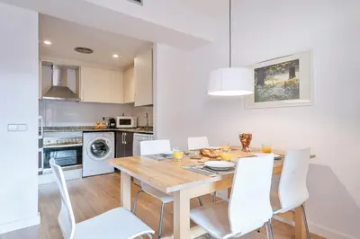 a kitchen and dining room with a wooden table and white chairs at Inside Barcelona Apartments Princep in Barcelona
