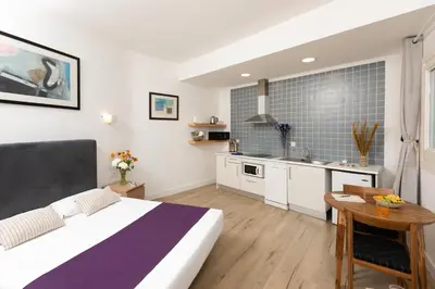 a bedroom with a large bed and a kitchen at Mayerling Bisbe Urquinaona in Barcelona