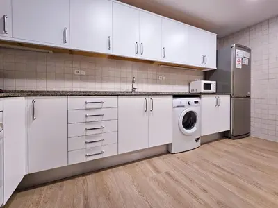 a kitchen with white cabinets and a washer and dryer at Classbedroom Park Güell Apartment in Barcelona