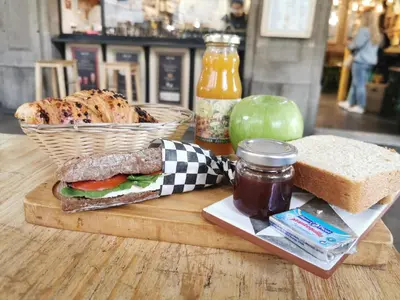 a sandwich on a cutting board with a basket of bread and jam at Ramblas Apartments in Barcelona
