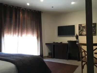 a bedroom with a bed and a desk and a television at Hotel Calabria in La Garriga