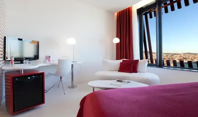a hotel room with a bed and a desk and a tv at Hotel Porta Fira 4* Sup in Hospitalet de Llobregat